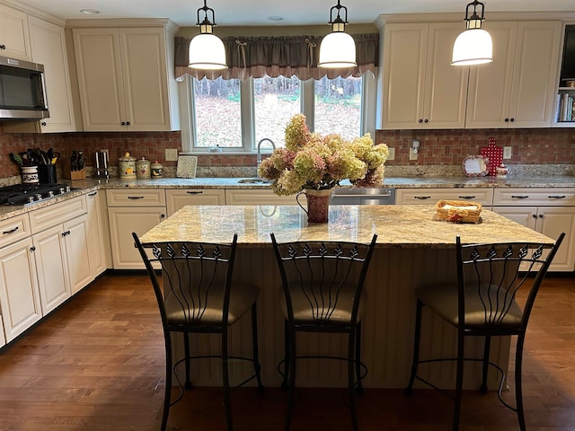 kitchen with decorative light fixtures, stainless steel appliances, dark wood-type flooring, and a center island