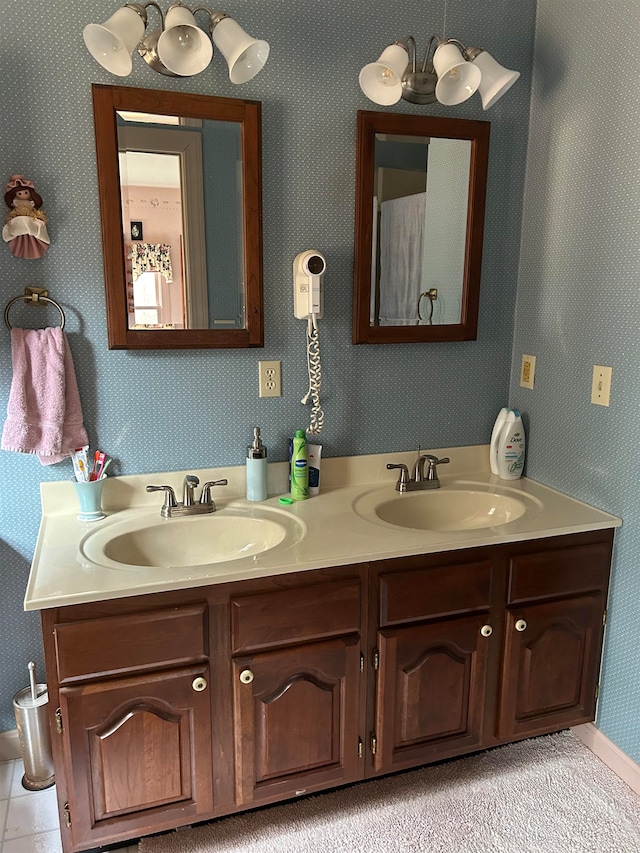full bathroom featuring double vanity, a sink, and wallpapered walls