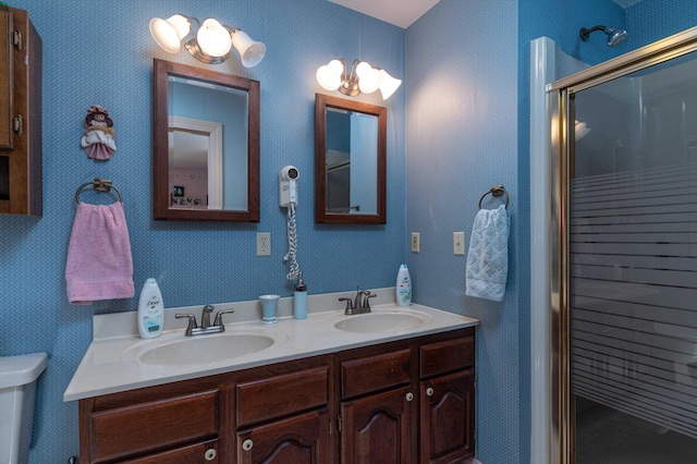 bathroom with an enclosed shower, double vanity, wallpapered walls, and a sink