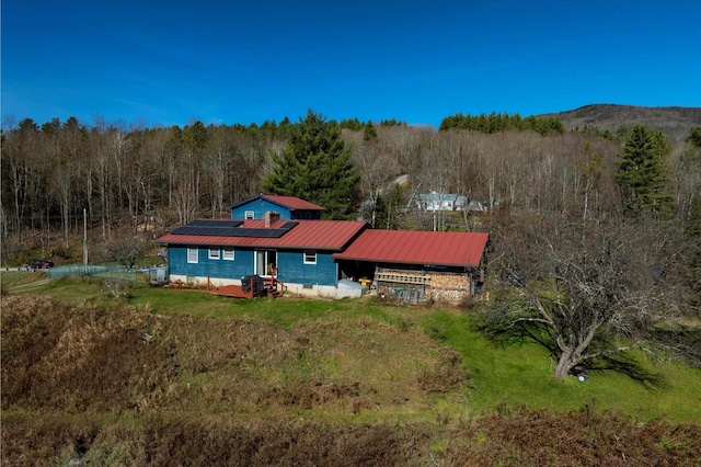 1319 Brandon Mountain Rd, Rochester, VT 05767 - rear view of house featuring solar panels, a wooded view, and metal roof