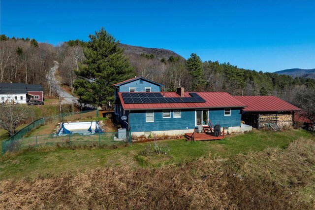 1319 Brandon Mountain Rd, Rochester, VT 05767 - back of property with solar panels, metal roof, a chimney, a forest view, and a patio