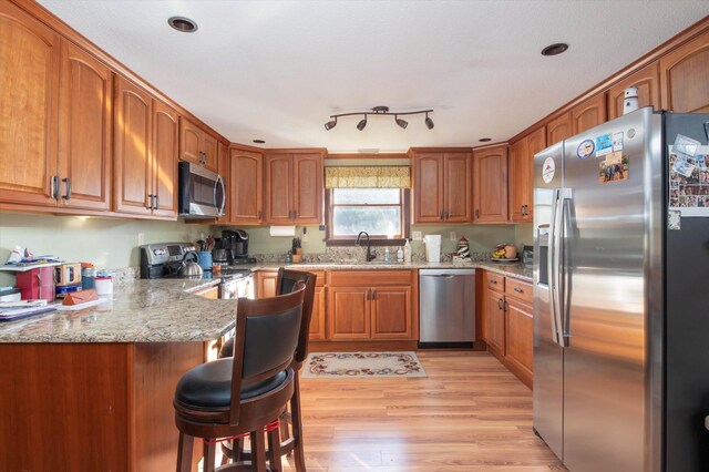 1319 Brandon Mountain Rd, Rochester, VT 05767 - kitchen with appliances with stainless steel finishes, a peninsula, brown cabinets, light stone countertops, and light wood-type flooring