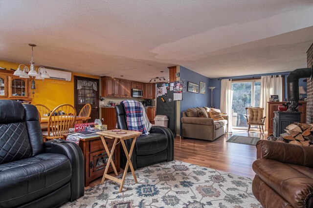 1319 Brandon Mountain Rd, Rochester, VT 05767 - living room featuring a chandelier, a wall unit AC, light wood finished floors, a wood stove, and a textured ceiling