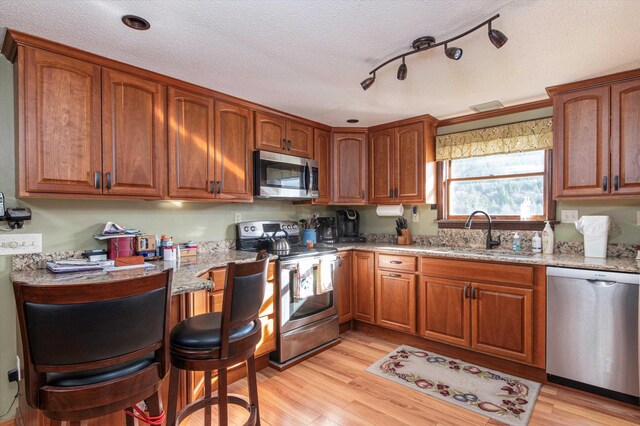 1319 Brandon Mountain Rd, Rochester, VT 05767 - kitchen featuring stainless steel appliances, a sink, light stone counters, brown cabinetry, and a textured ceiling