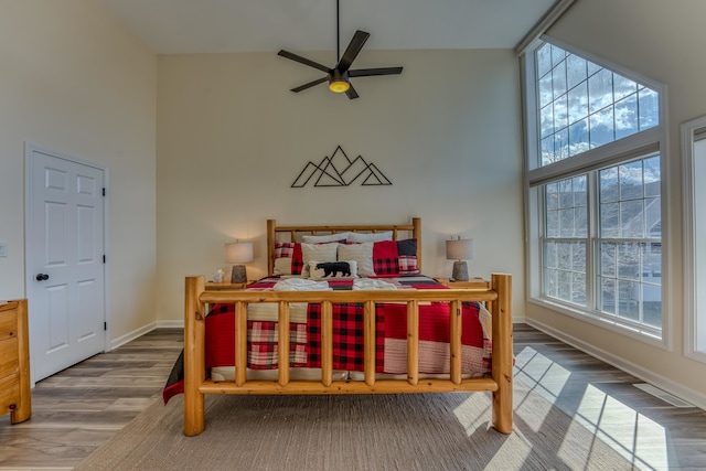 bedroom featuring a towering ceiling, hardwood / wood-style flooring, and ceiling fan