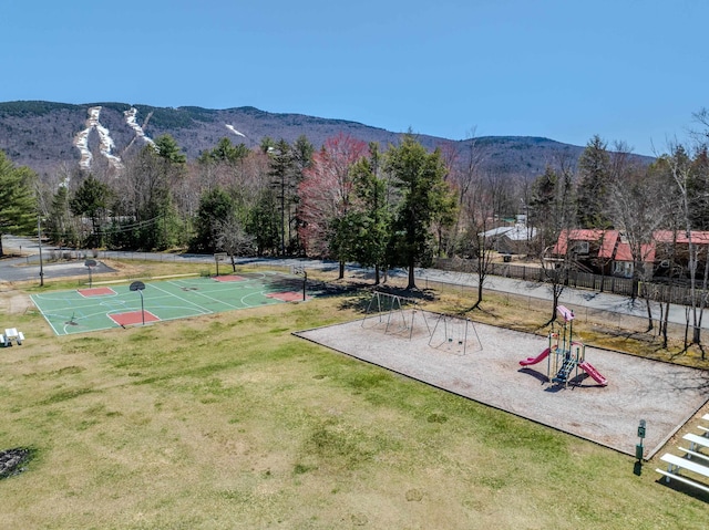 surrounding community with basketball hoop, a mountain view, a playground, and a lawn