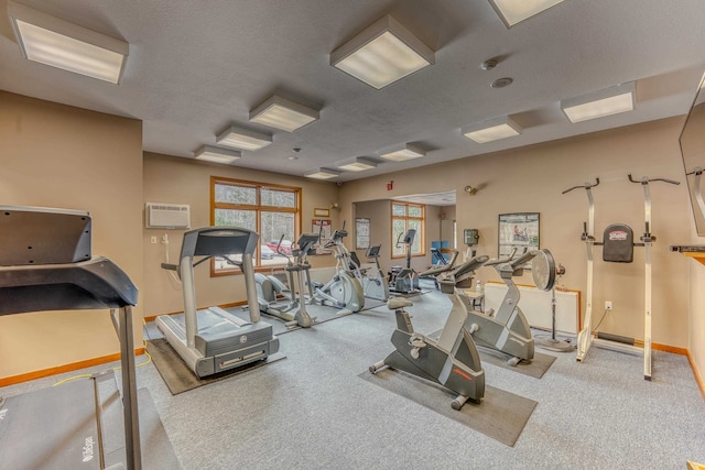 exercise room with a wall mounted air conditioner and a textured ceiling