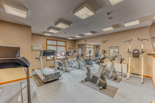 exercise room featuring a textured ceiling and an AC wall unit