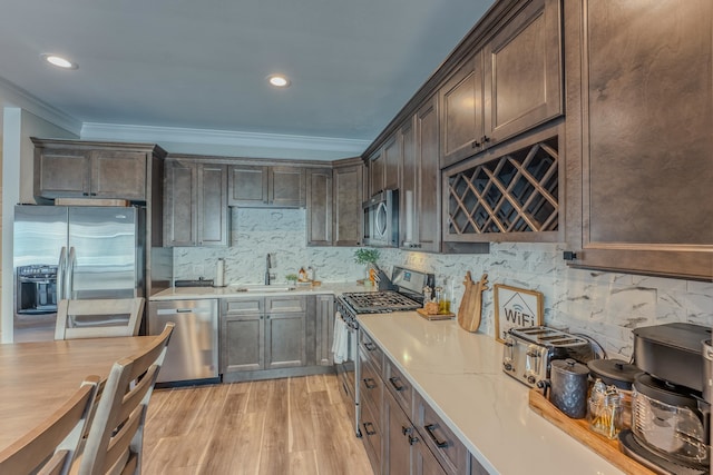 kitchen featuring sink, light hardwood / wood-style flooring, tasteful backsplash, dark brown cabinets, and stainless steel appliances