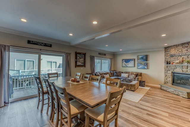 dining space featuring a fireplace, light wood-type flooring, and crown molding