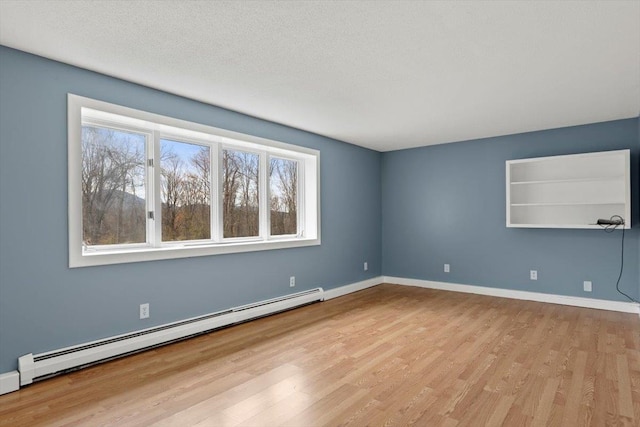 unfurnished room with light wood-type flooring, a textured ceiling, and a baseboard radiator