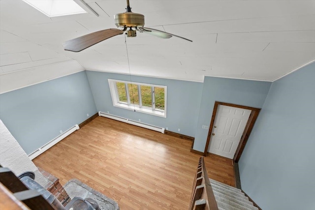 additional living space with ceiling fan, a baseboard radiator, and hardwood / wood-style flooring