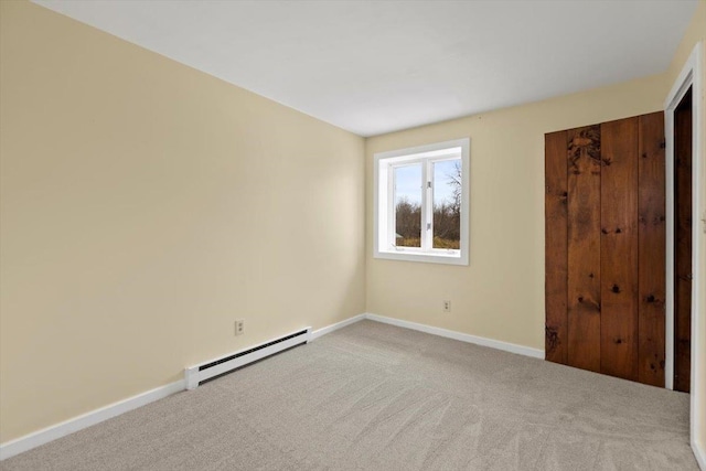 empty room featuring light carpet and a baseboard heating unit