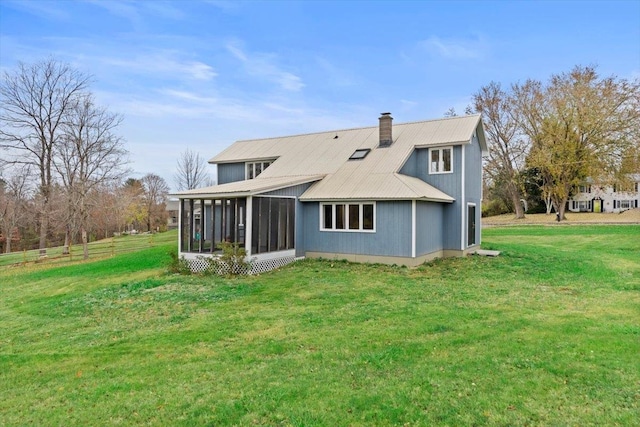 rear view of property featuring a lawn and a sunroom