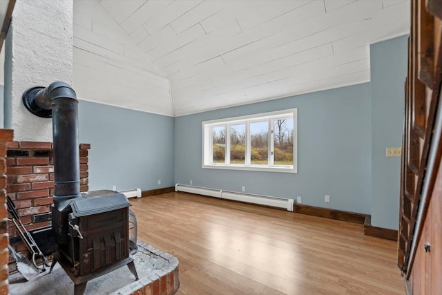 living room with light wood-type flooring, vaulted ceiling, a wood stove, and a baseboard heating unit