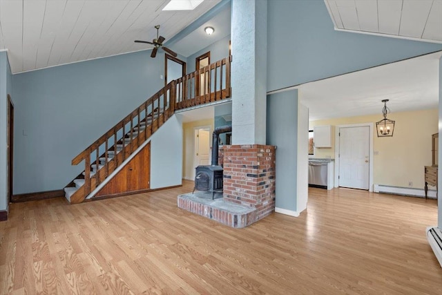 living room featuring light wood-type flooring, a baseboard radiator, a wood stove, and high vaulted ceiling