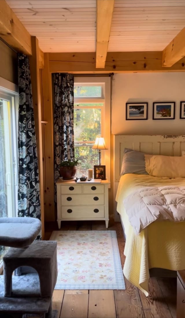 bedroom featuring beam ceiling, multiple windows, hardwood / wood-style floors, and wooden ceiling