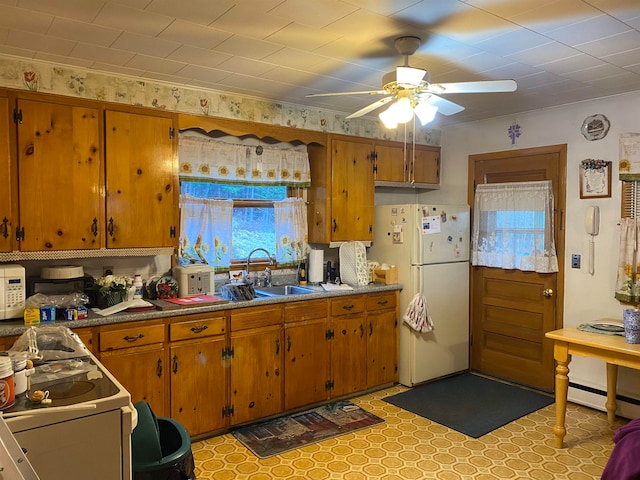 kitchen featuring white appliances, baseboard heating, ceiling fan, and sink