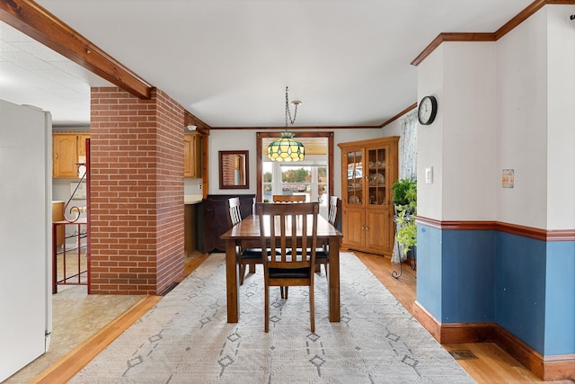 dining room featuring light hardwood / wood-style flooring, crown molding, and decorative columns