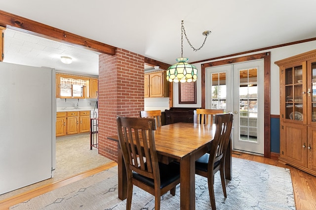 dining space featuring light wood-type flooring, crown molding, and decorative columns