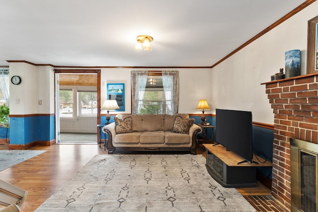 living room with ornamental molding, a brick fireplace, and wood-type flooring