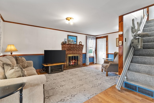 living room featuring hardwood / wood-style floors, crown molding, and a brick fireplace