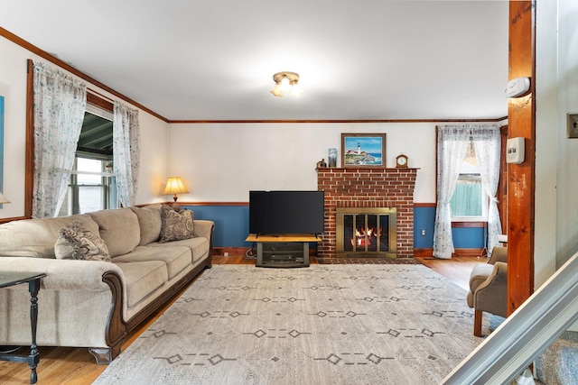 living room with hardwood / wood-style floors, ornamental molding, and a brick fireplace