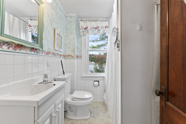 bathroom featuring toilet, vanity, and tile walls