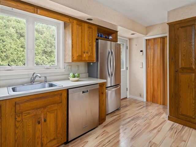 67 Case Pkwy, Burlington, VT 05401 - kitchen with stainless steel appliances, a sink, brown cabinetry, light countertops, and light wood-style floors