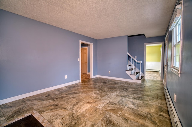 empty room with a textured ceiling and baseboard heating