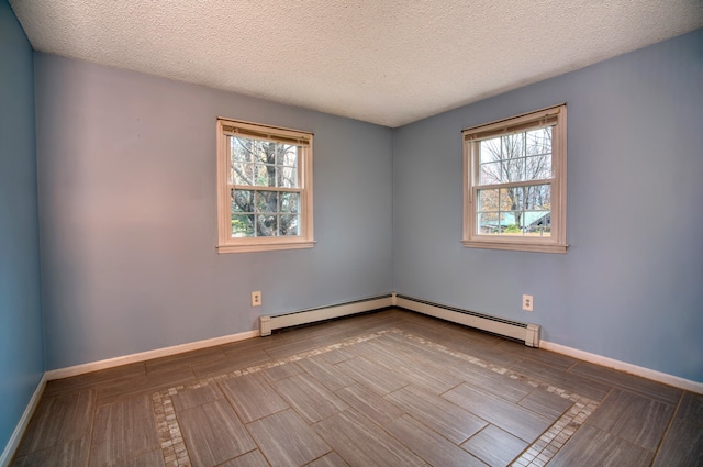 spare room featuring a baseboard heating unit, a healthy amount of sunlight, and a textured ceiling