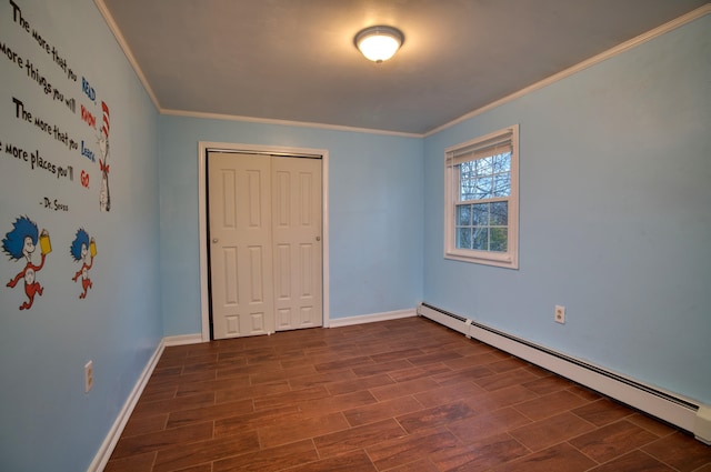 unfurnished bedroom with a baseboard heating unit, dark wood-type flooring, ornamental molding, and a closet