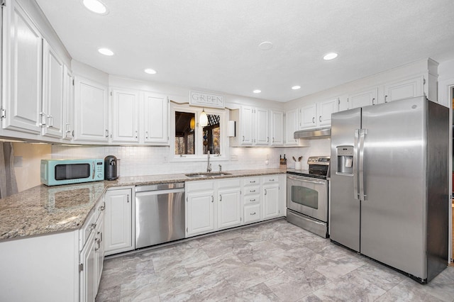 kitchen with light stone countertops, white cabinets, sink, and stainless steel appliances