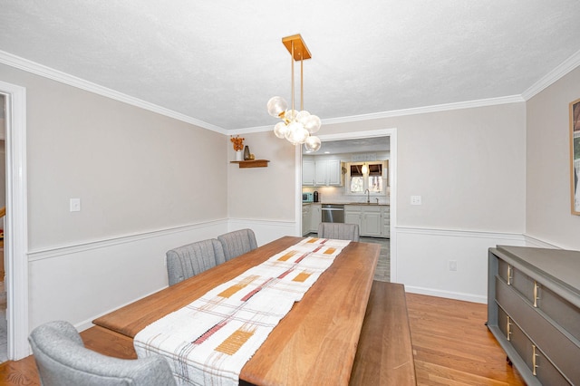 dining room with light hardwood / wood-style flooring, a notable chandelier, a textured ceiling, and crown molding