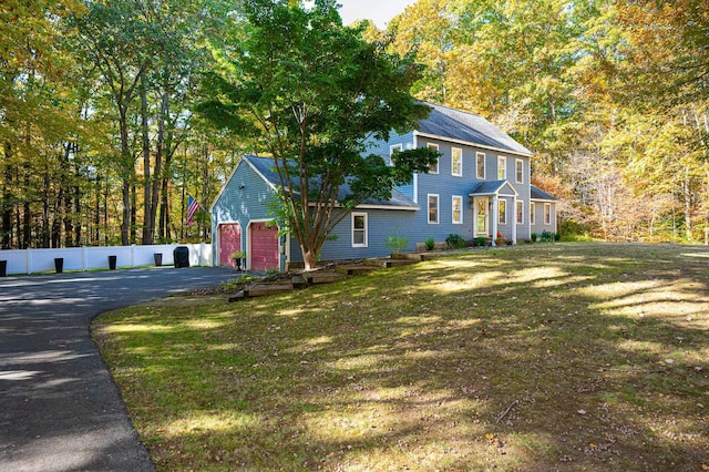 colonial-style house featuring a garage and a front lawn