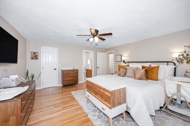 bedroom featuring light wood-type flooring, a textured ceiling, ceiling fan, and ensuite bathroom