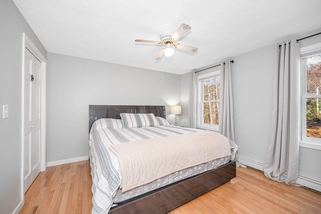 bedroom with baseboard heating, light wood-type flooring, and ceiling fan