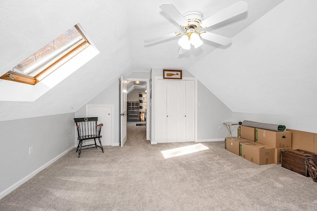 bonus room with lofted ceiling with skylight, light colored carpet, and ceiling fan