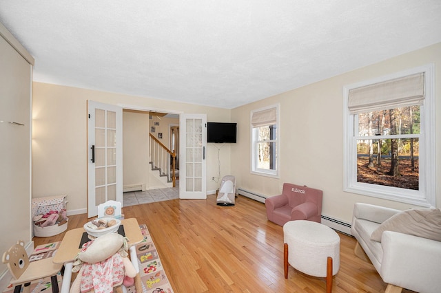 living room with hardwood / wood-style floors, baseboard heating, and french doors