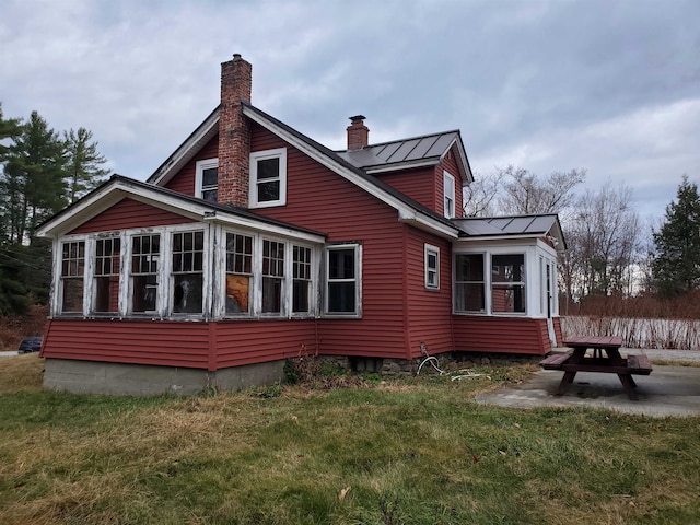 back of house with a fire pit, a sunroom, a yard, and a patio area