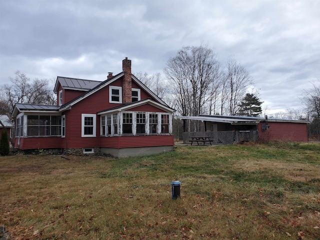 rear view of property with a lawn and a sunroom