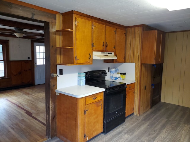 kitchen featuring wood walls, black / electric stove, and hardwood / wood-style floors