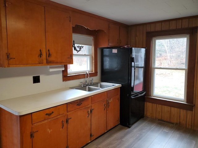 kitchen featuring light hardwood / wood-style floors, plenty of natural light, black fridge, and sink