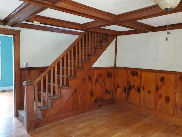 stairway featuring wood walls, beamed ceiling, and wood-type flooring