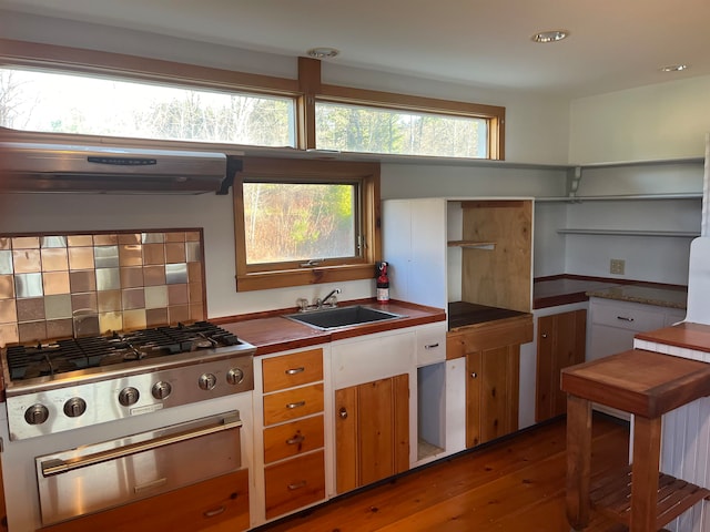 kitchen featuring hardwood / wood-style floors, decorative backsplash, stainless steel gas cooktop, sink, and ventilation hood