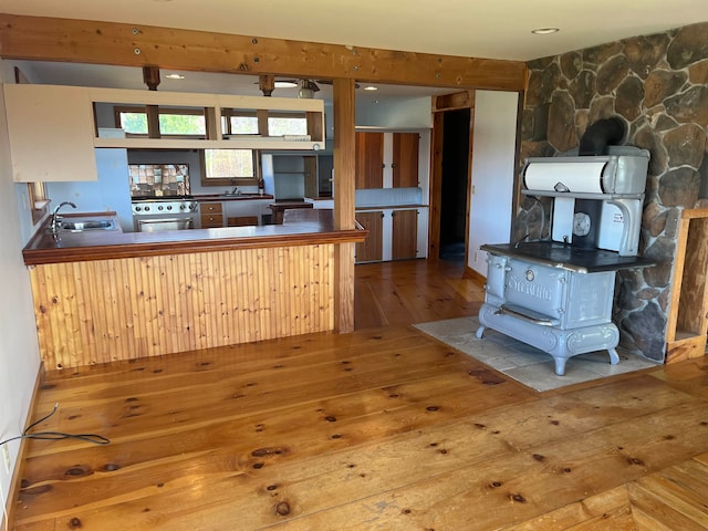 kitchen featuring high end stainless steel range oven, kitchen peninsula, sink, and light hardwood / wood-style flooring