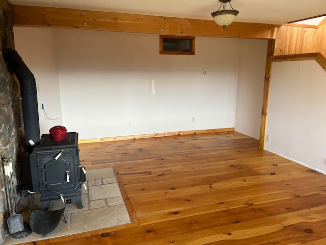 spare room with a wood stove and wood-type flooring