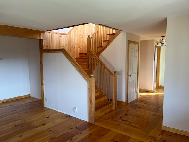 staircase with a chandelier and wood-type flooring