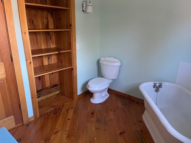 bathroom with hardwood / wood-style flooring, a bathing tub, and toilet