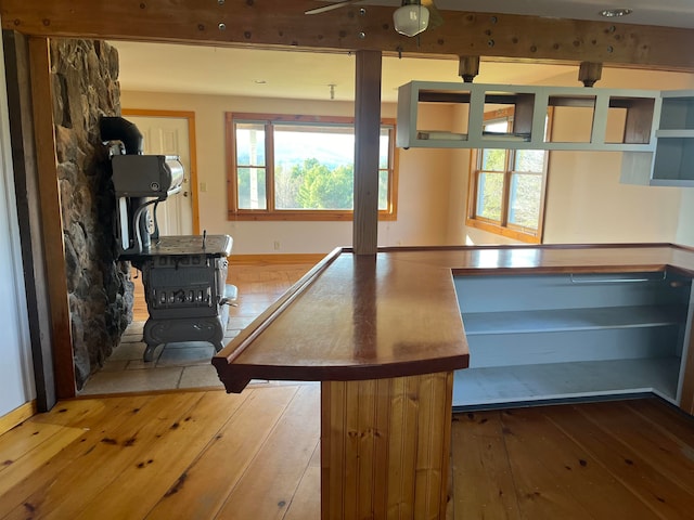 kitchen with hardwood / wood-style flooring, plenty of natural light, and a wood stove